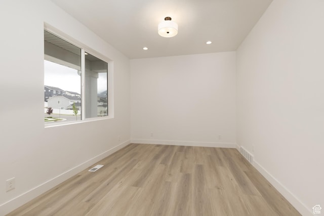empty room with light wood-style flooring, baseboards, and recessed lighting