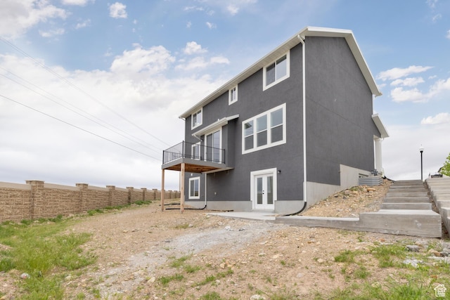 back of house featuring french doors, stucco siding, fence, and a deck