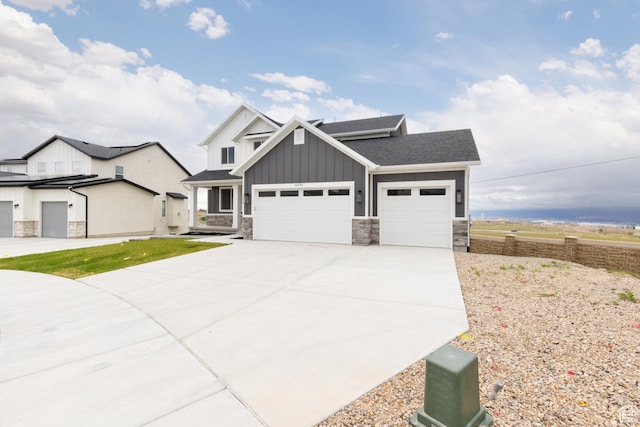 view of front of house featuring board and batten siding, stone siding, an attached garage, driveway, and roof with shingles