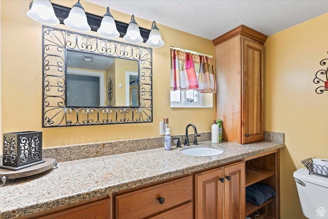 bathroom with toilet, vanity, and a textured ceiling