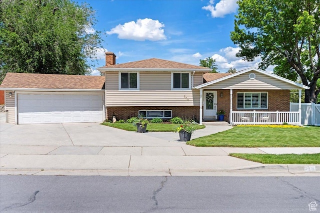 tri-level home featuring a chimney, brick siding, a porch, and concrete driveway