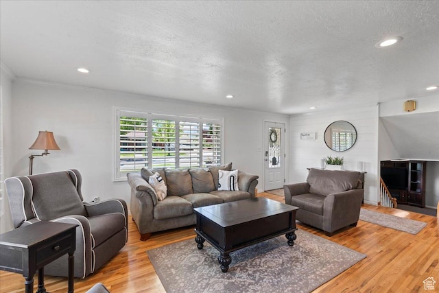 living area with wood finished floors, recessed lighting, a textured ceiling, and crown molding