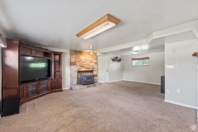 unfurnished living room featuring a wood stove, carpet, baseboards, and a textured ceiling