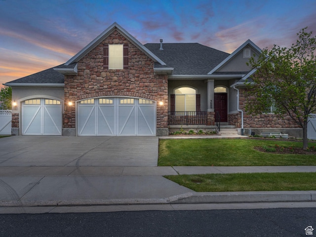 craftsman house with stone siding, driveway, a lawn, and stucco siding