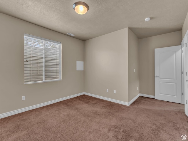 carpeted empty room with baseboards and a textured ceiling