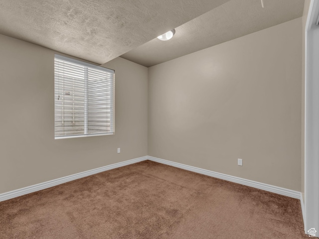 carpeted empty room featuring a textured ceiling and baseboards