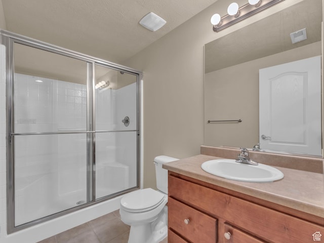 full bathroom with tile patterned flooring, a shower stall, toilet, vanity, and a textured ceiling