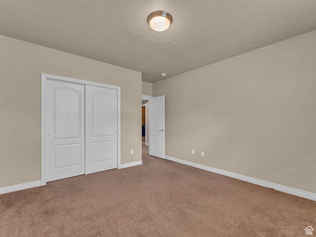 unfurnished bedroom with carpet flooring, baseboards, a closet, and a textured ceiling