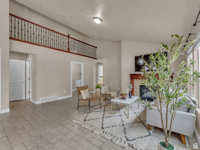 living area featuring a tiled fireplace, high vaulted ceiling, baseboards, and arched walkways