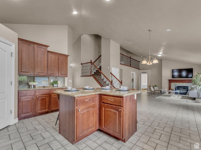 kitchen featuring lofted ceiling, open floor plan, a center island, light stone countertops, and recessed lighting