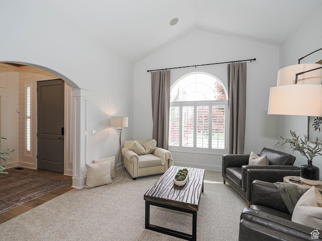 living area featuring arched walkways, lofted ceiling, wood finished floors, and baseboards