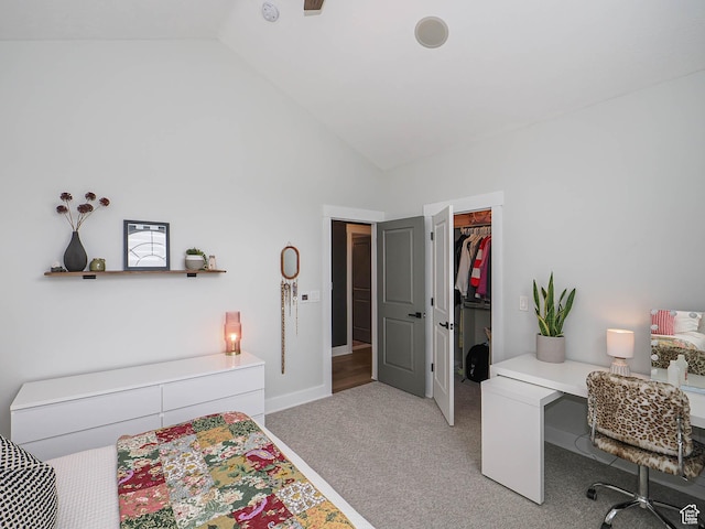 bedroom with light carpet, a walk in closet, a desk, a closet, and high vaulted ceiling