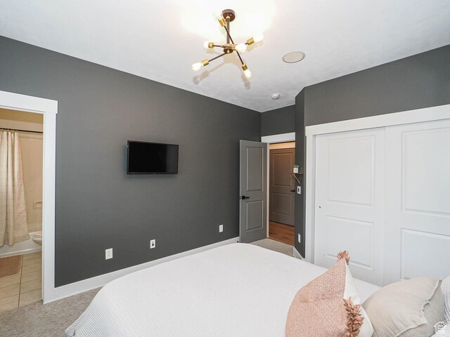 bedroom featuring a chandelier, a closet, baseboards, light carpet, and ensuite bathroom