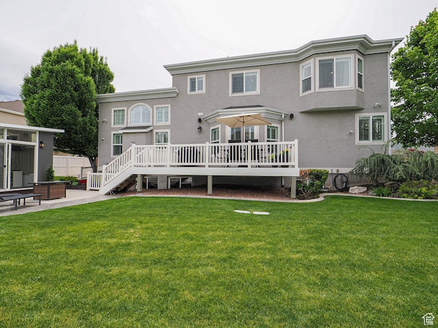 back of house featuring stucco siding, a wooden deck, a yard, and a patio area