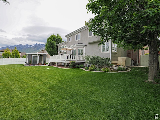 back of property with a sunroom, a deck with mountain view, and stucco siding