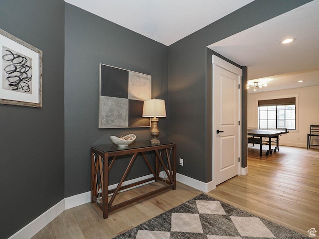 hall with wood finished floors, baseboards, a chandelier, and recessed lighting