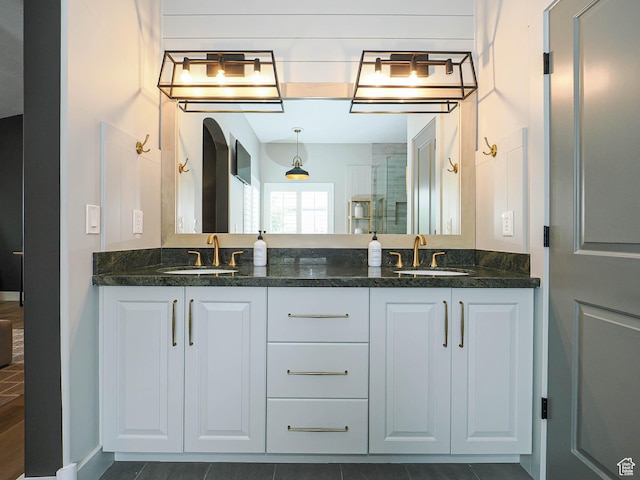 full bathroom featuring a shower stall, double vanity, and baseboards