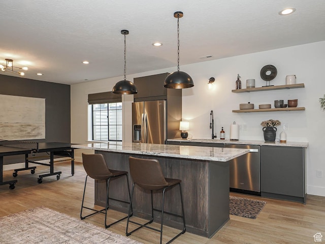 kitchen with appliances with stainless steel finishes, a sink, light wood finished floors, a center island, and recessed lighting