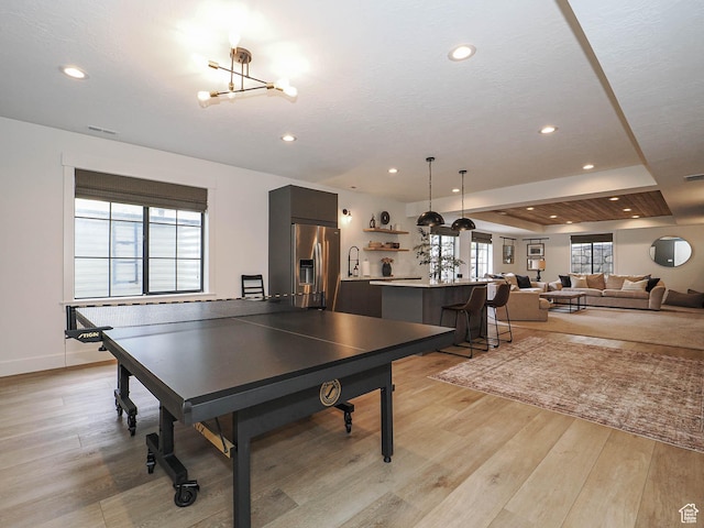 recreation room featuring light wood-type flooring, baseboards, recessed lighting, a chandelier, and a sink