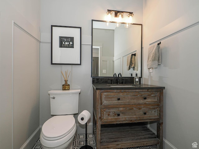 bathroom featuring toilet, vanity, and baseboards