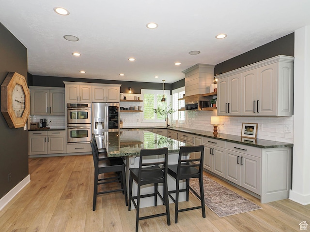 kitchen with open shelves, stainless steel appliances, a breakfast bar, backsplash, and recessed lighting