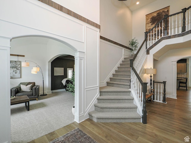 foyer featuring arched walkways, ornate columns, wood finished floors, recessed lighting, and stairs