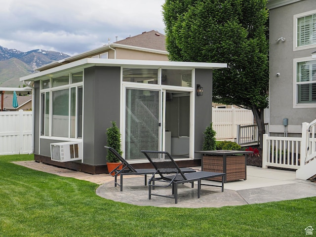 back of property with a sunroom, a mountain view, a patio, and stucco siding