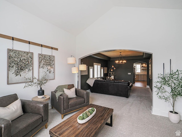 living area with arched walkways, carpet, a chandelier, high vaulted ceiling, and baseboards