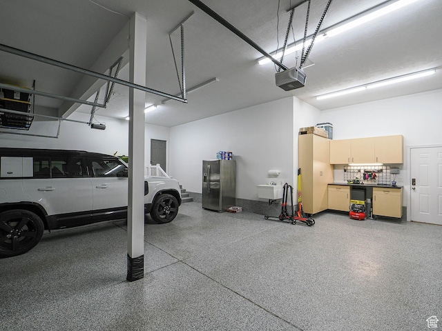 garage with a garage door opener and stainless steel fridge with ice dispenser