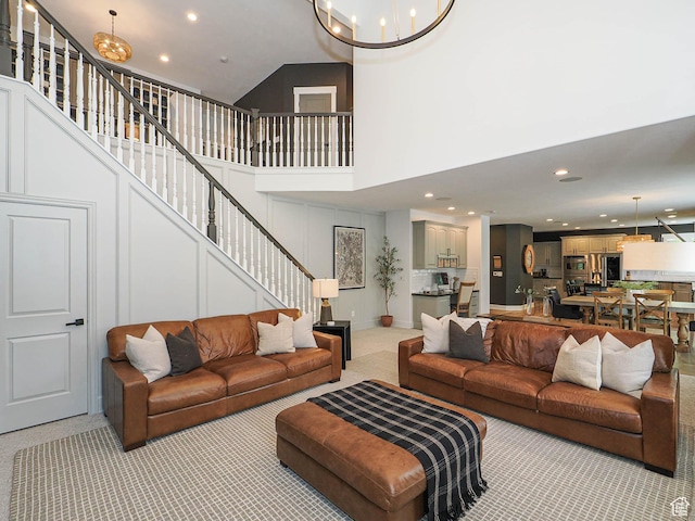 living area with a chandelier, stairs, light carpet, recessed lighting, and a high ceiling