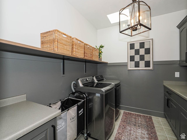 washroom with cabinet space, washer and dryer, a chandelier, a skylight, and light tile patterned flooring