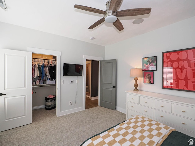 bedroom featuring light carpet, a spacious closet, a closet, baseboards, and a ceiling fan