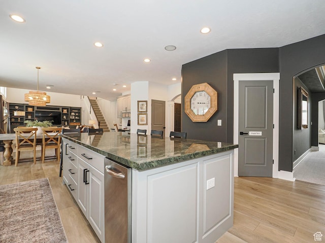 kitchen with arched walkways, white cabinets, light wood finished floors, recessed lighting, and a spacious island