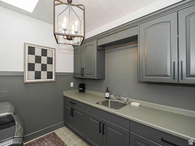 clothes washing area featuring cabinet space, baseboards, a chandelier, and light tile patterned flooring