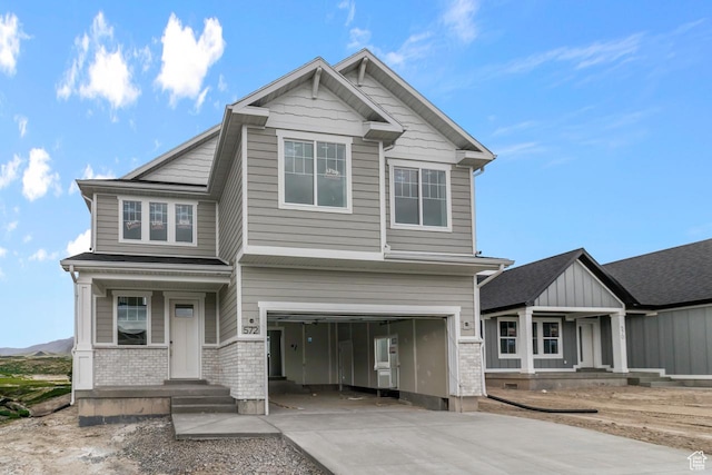 craftsman inspired home featuring covered porch, an attached garage, driveway, and brick siding
