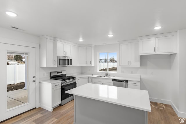 kitchen with appliances with stainless steel finishes, a sink, plenty of natural light, white cabinets, and recessed lighting