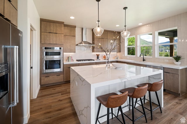 1015 W Sugar Maple Dr, Mapleton, UT 84664 - kitchen with stainless steel appliances, wall chimney range hood, a sink, dark wood-style floors, and a breakfast bar area