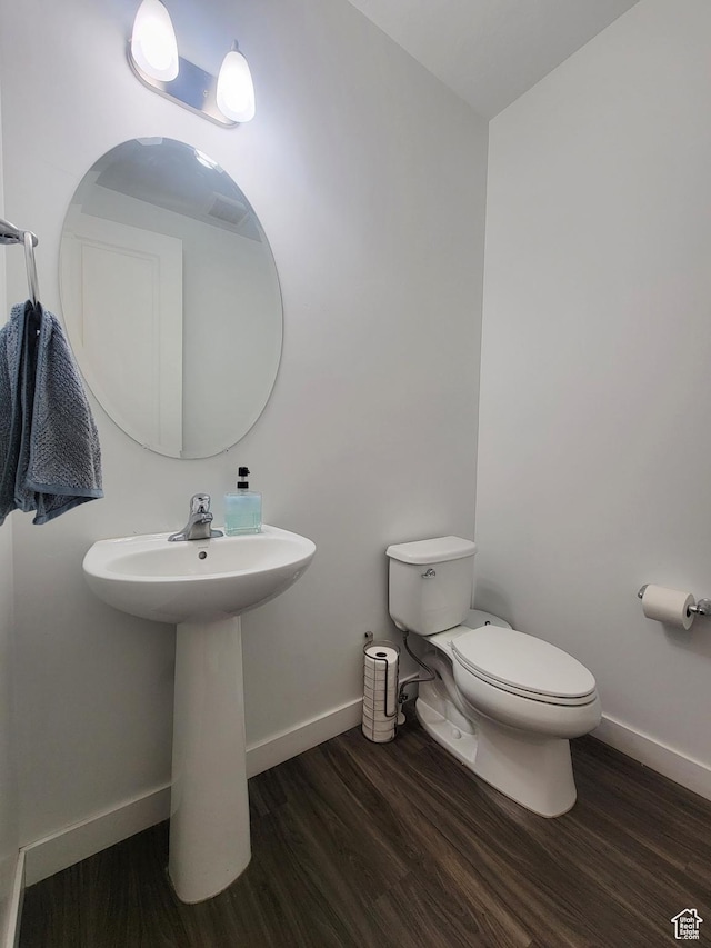 bathroom featuring wood finished floors, toilet, baseboards, and a sink