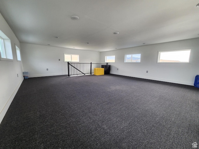spare room with dark carpet and baseboards