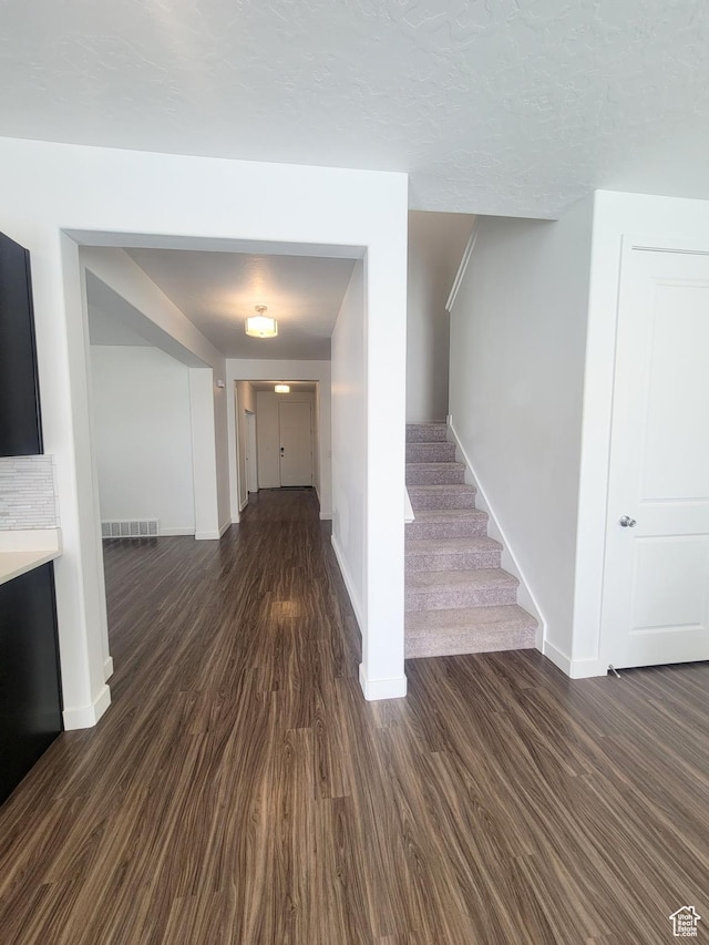 hall featuring baseboards, dark wood-style flooring, and stairs