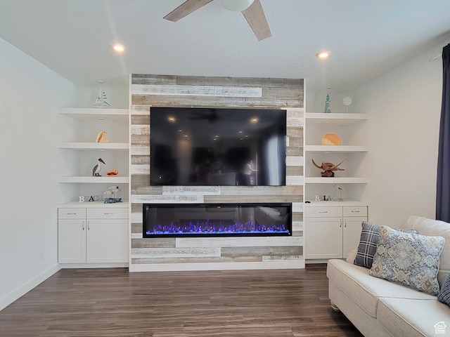 living area with dark wood-style flooring, a ceiling fan, a large fireplace, baseboards, and recessed lighting