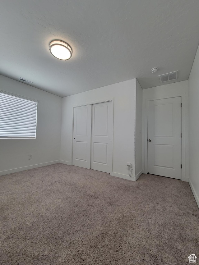 unfurnished bedroom with baseboards, carpet flooring, and a closet