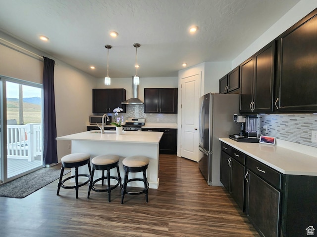 kitchen featuring appliances with stainless steel finishes, backsplash, an island with sink, a breakfast bar area, and light countertops