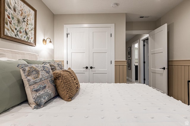 bedroom featuring a closet and a wainscoted wall