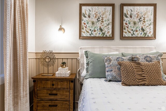 bedroom with wainscoting and a decorative wall