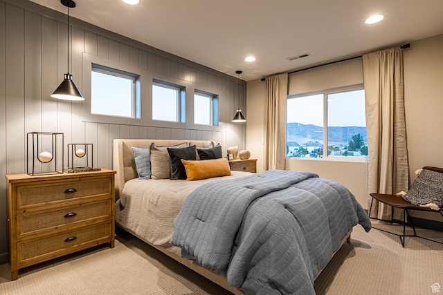 bedroom with light carpet, recessed lighting, a mountain view, and a decorative wall