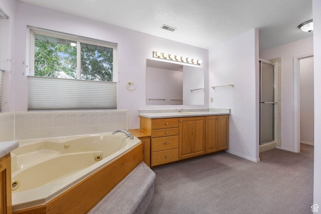 full bathroom featuring vanity, a shower stall, a jetted tub, a textured ceiling, and baseboards