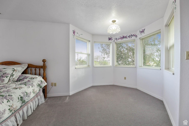 carpeted bedroom featuring multiple windows, a textured ceiling, a chandelier, and baseboards