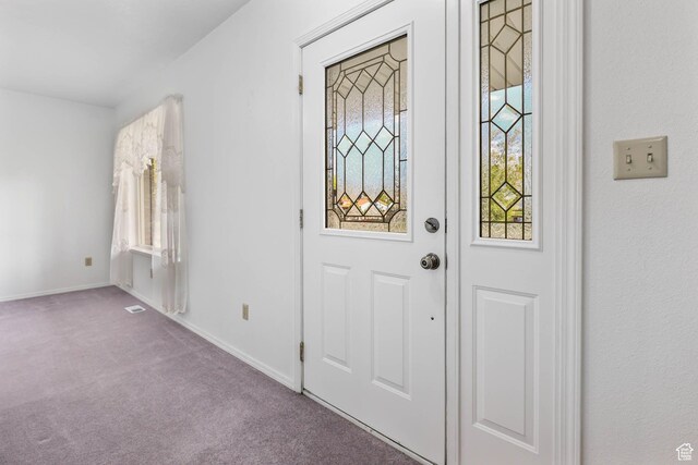 foyer entrance featuring carpet and baseboards