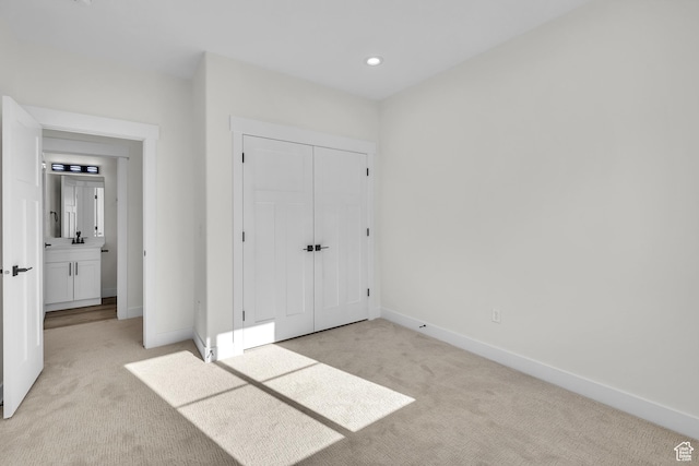 unfurnished bedroom featuring light carpet, baseboards, recessed lighting, and a closet